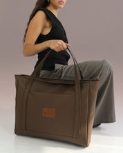 תיק צד פלא חום קלאסי של זנדיגי מוחזק בידה של דוגמנית, תיק צד טבעוני ואיכותי שילווה אותך לאורך שנים.