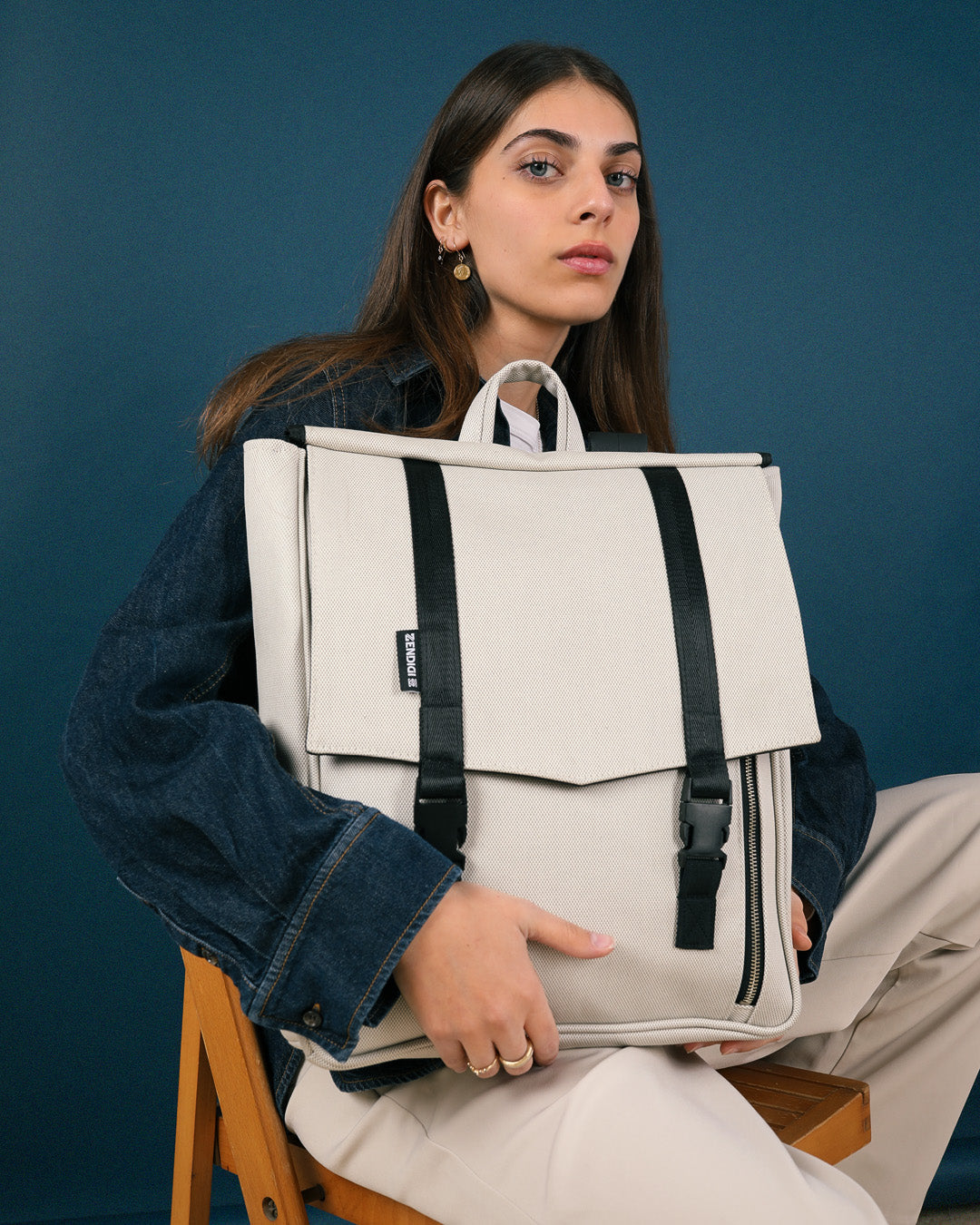 אישה מחזיקה את תיק גב טוקיו בינגו שמנת החדש, תיק גב למחשב נייד 16״, מתאים לסטודנטים ולהייטקיסטים, תיק עבודה קלאסי ונוח.